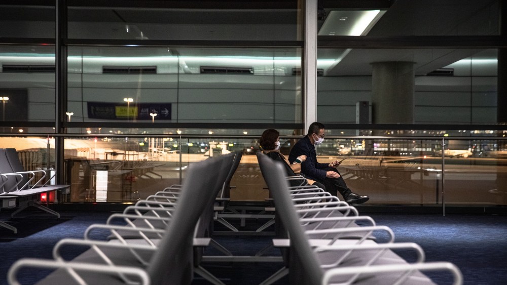 Passengers wearing protective masks sit in the empty hall of Shanghai Pudong Airport in Shanghai, China.