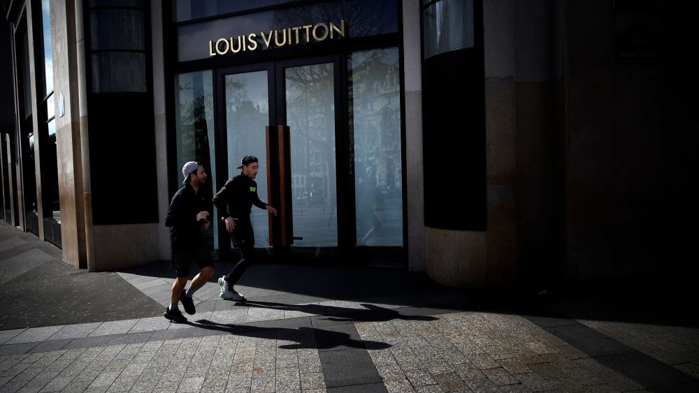 Men jog past Louis Vuitton store on the Champs-Elysees avenue in Paris, . French Prime Minister Edouard Philippe announced that France is shutting down all restaurants, cafes, cinemas and non-essential retail shops, starting Sunday, to combat the accelerated spread of the virus in the country. For most people, the new coronavirus causes only mild or moderate symptoms. For some it can cause more severe illnessVirus Outbreak, Paris, France - 15 Mar 2020
