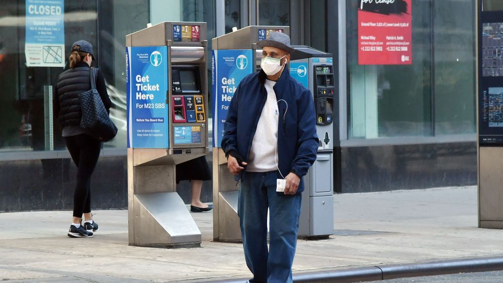 A pedestrian wearing a face mask hails a cabCoronavirus Outbreak, New York, USA - 18 Mar 2020
