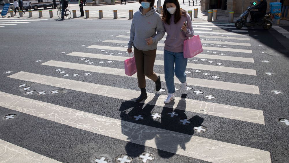 Shoppers cross the road near a deserted shopping district in Beijing on . Even while social distancing and quarantines for new arrivals remain the norm, China is striving to restore activity in the world's second-largest economyVirus Outbreak , Beijing, China - 22 Mar 2020