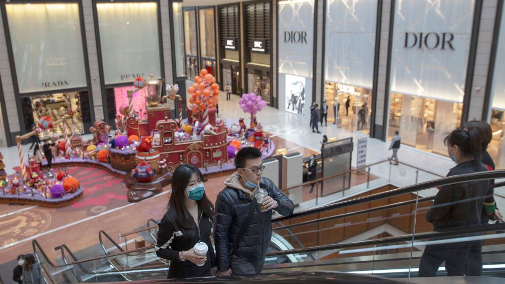 People wearing protective face masks stand on an escalator in a shopping mall where many luxury store opened in Beijing, China, 26 March 2020. Chinese people are going back to normal daily life after COVID-19 coronavirus outbreak in China.Chinese people going back to normal daily life after COVID-19 coronavirus outbreak in China, Beijing - 26 Mar 2020