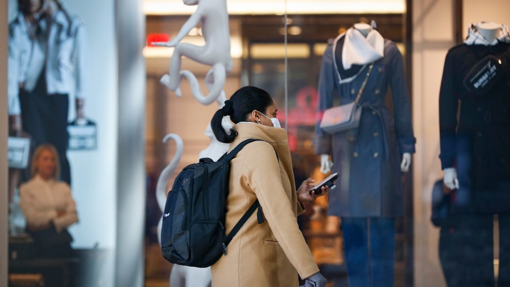 Pedestrian wearing a face mask passes a retail store as an attendant looks, in New York. New York leaders took a series of unprecedented steps Sunday to slow the spread of the coronavirus, including canceling schools and extinguishing most nightlife in New York CityVirus Outbreak , New York, United States - 16 Mar 2020