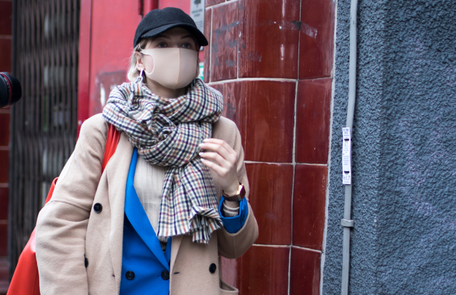 London, UK - 10 February, 2020 People wear mask for protection. Street style. Stylish woman in black dress, coat and a cap wears a beige mask. London fashion week; Shutterstock ID 1646151625; Usage (Print, Web, Both): Web; Issue Date: April 7; Comments: WWD