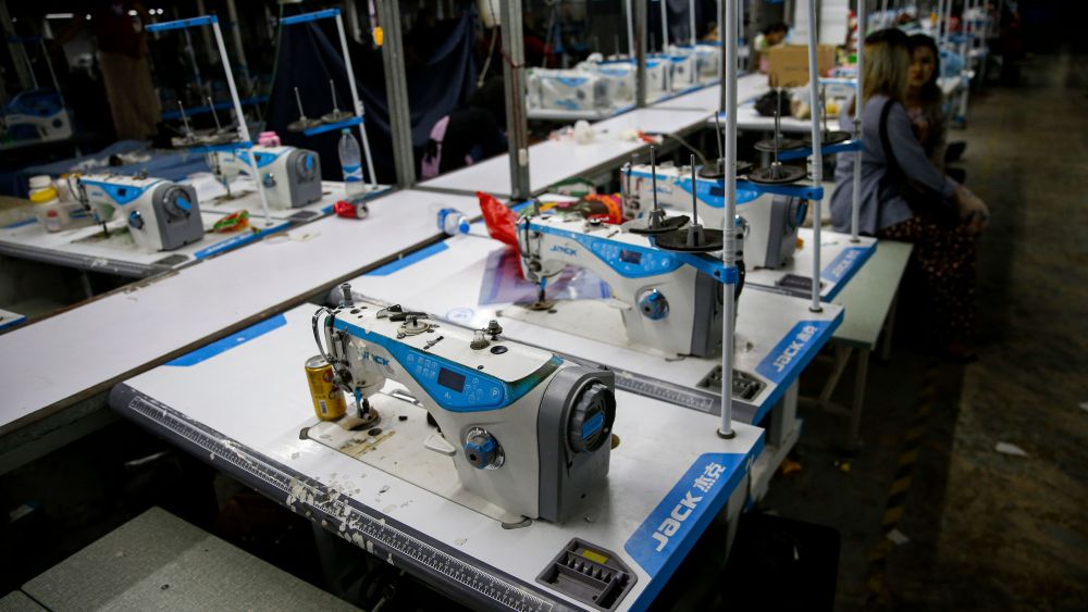 Two workers sit near sewing machines.