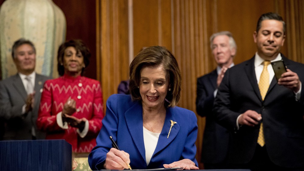 House Speaker Nancy Pelosi of Calif., accompanied by bipartisan legislators, signs the Coronavirus Aid, Relief, and Economic Security (CARES) Act after it passed in the House on Capitol Hill, in Washington. The $2.2 trillion package will head to head to President Donald Trump for his signatureVirus Outbreak Congress, Washington, United States - 27 Mar 2020