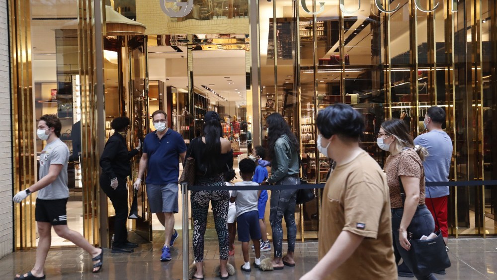 Amid concerns of the spread of COVID-19, a shopper leaves a Gucci store as other wait to enter at North Park Mall in Dallas, . Texas charged into its first weekend of re-opening the economy with residents allowed to go back to malls, restaurants, movie theaters and retail stores in limited numbersVirus Outbreak Texas Daily Life, Dallas, United States - 02 May 2020
