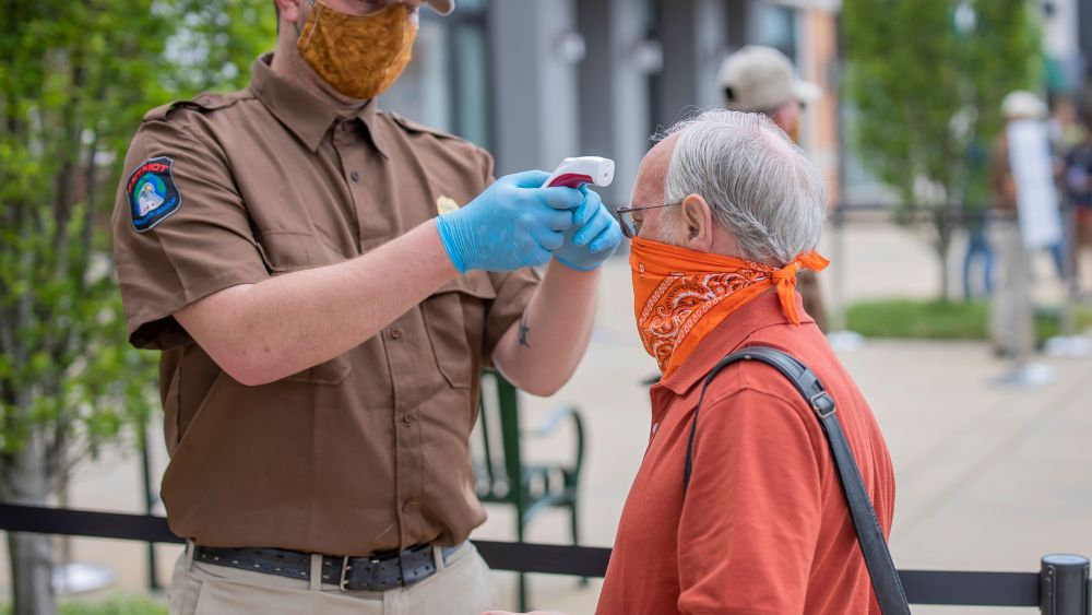 A customer has their temperature checked before being allowed to enter a reopened Apple store during the coronavirus pandemic in Alabama.