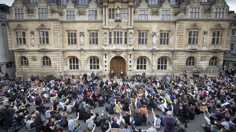 Campaigners sit in the road outside Oriel College at Oxford University, where they are calling for the removal of a statue of controversial imperialist Cecil Rhodes. Black Lives Matter protesters recently pulled down a statue of slave trader Edward Colston in Bristol town centre, following the death of George Floyd in the USACecil Rhodes protest, Oxford, UK - 09 Jun 2020