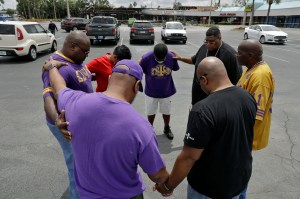 Members of the Omega Psi Phi fraternity praying in a parking lot, in Tampa, Florida where two places of business, including a sporting good store, were destroyed.