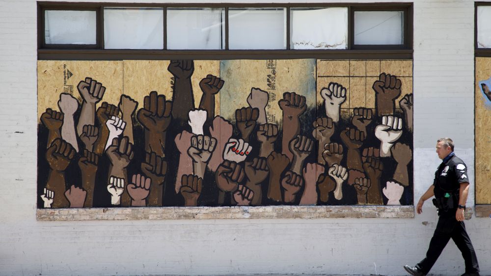 A Los Angeles Police Department LAPD officer walks past street art of raised fists on a boarded-up business near a demonstration protesting the police killing of George Floyd, in Los Angeles, California USA, 08 June 2020. Funeral services for George Floyd are ongoing in Houston, Texas as protests continue across the US.Memorial protest for George Floyd in Los Angeles, USA - 08 Jun 2020