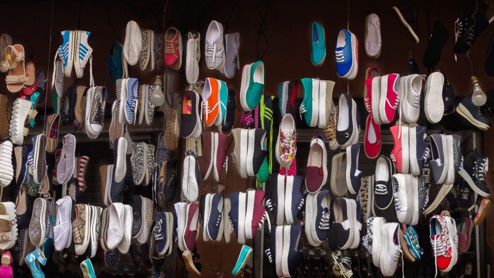 Lots of different shoes hanging on the rope in the showcase of market