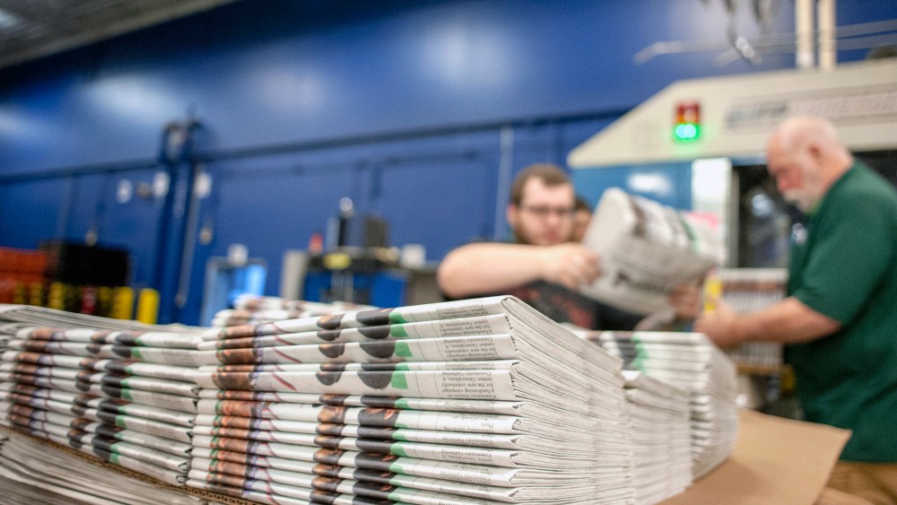 FILE - In this April 11, 2018, file photo, production workers stack newspapers onto a cart at the Janesville Gazette Printing & Distribution plant in Janesville, Wis. The U.S. Commerce Department is going ahead with a tax on Canadian newsprint, a threat to the already-struggling American newspaper industry. The tariffs unveiled Thursday, Aug. 2, are mostly lower than those originally announced earlier this year but would still impose an anti-dumping border tax as high as 16.88 percent. (Angela Major/The Janesville Gazette via AP, File)