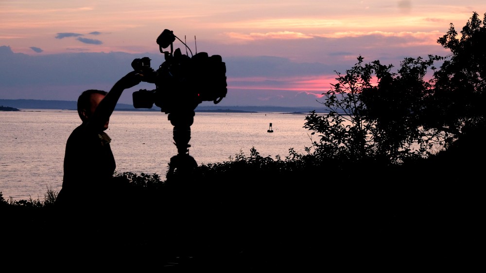 A member of a TV crew adjusts their camera while filming near the shore of Bailey Island, Maine, where a woman swimming off the coast was killed in an apparent shark attack Monday, July 27, 2020. Two kayakers helped the person get to shore, and an ambulance provided further assistance, but she was pronounced dead at the scene, Marine Patrol said. (AP Photo/Jim Gerberich)
