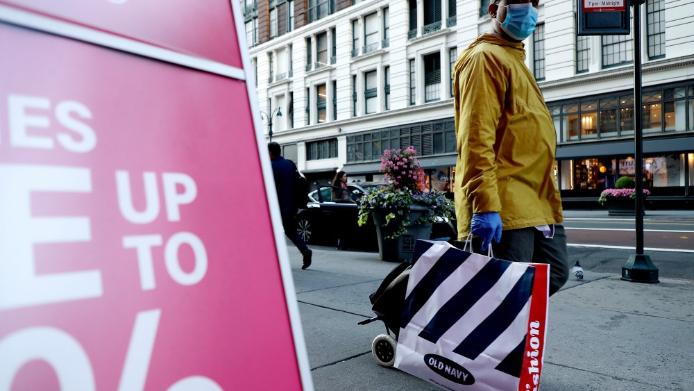 A shopper walks with bags of purchases. Pedestrian and vehicular traffic have noticeably increased as businesses mark the next phase of reopening the economy today in New York City, US. As the city moves towards reopening the economy, post the COVID-19 pandemic, professional services, finance, real estate, administrative support and outdoor dining, will mark the phase two of four stages of reopening. (Photo by John Lamparski / SOPA Images/Sipa USA)(Sipa via AP Images)