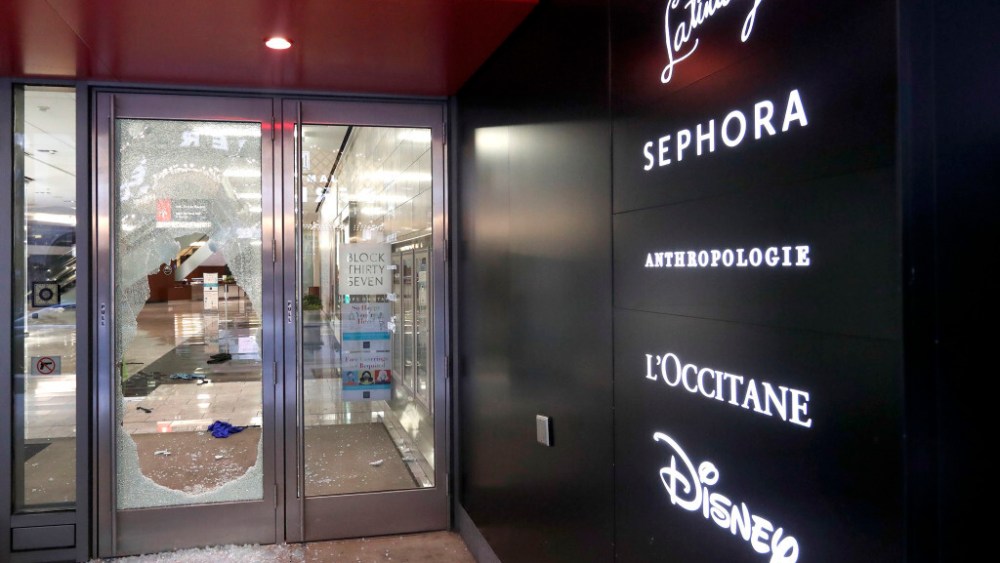 A door to the Block 37 retail building is shattered Monday, Aug. 10, 2020, after vandals struck overnight in Chicago's famed Loop. Chicago’s police commissioner says more than 100 people were arrested following a night of looting and unrest that left several officers injured and caused damage in the city’s upscale Magnificent Mile shopping district and other parts of the city. (AP Photo/Charles Rex Arbogast)