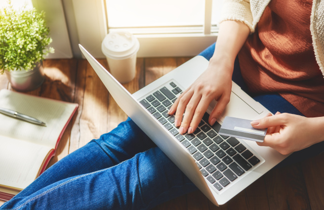 Woman is holding credit card and using laptop computer. Online shopping concept. Close up.