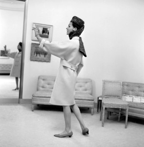 A model poses backstage in the single seamed "yoke" sleeved coat for the Cristobal Balenciaga fall 1965 couture season.