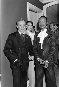Designer Adolfo poses with models in his feminized version of the male pin-striped suit for fall 1976.