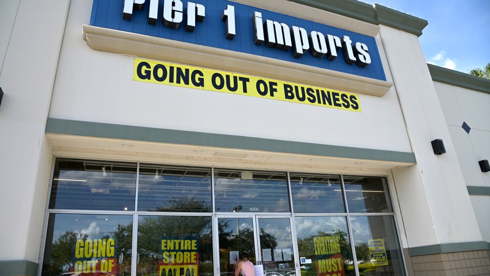 A shopper peers into a closed Pier 1 Imports store, Monday, Aug. 3, 2020, in Orlando, Fla. The chain plans to shutter all stores and liquidate due to COVID-19. Many beaches and businesses have reopened during the new coronavirus pandemic. (Phelan M. Ebenhack via AP)