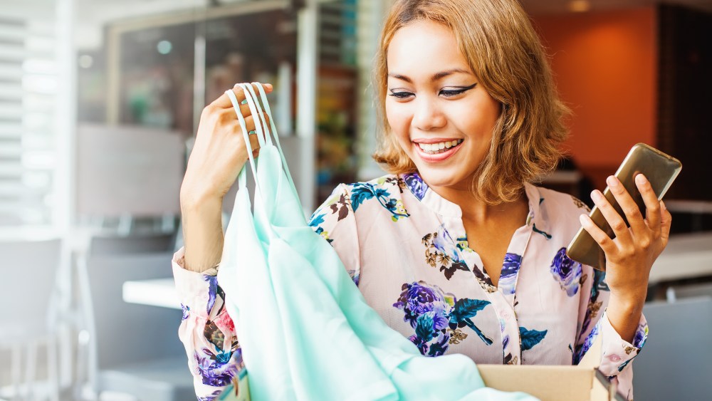 woman with phone opening box of clothes