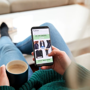 Close Up Of Woman Shopping For Clothes Online Using Mobile Phone App