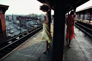 Subway platform. New York City. USA.1980 

"I took this image on the elevated M Line at the Myrtle Avenue-Wyckoff Avenue stop in Bushwick, Brooklyn, as part of my Subway series. I saw this wonderful color-play between the two women – one wore a yellow dress with green shoes, the other was in red. As I was getting ready to click the shutter, the wind caught the dress of the women in yellow. It wasn't blowing it up around her knees like a Marilyn Monroe picture, it was just fluffing it. It was a delicate moment.”
– Bruce Davidson
