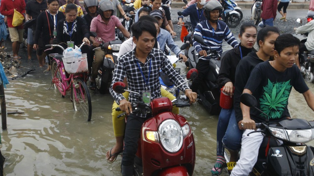 Garment workers make their way to work through a flooded street in Cambodia.