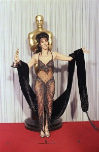 Cher shows off both her Oscar and Bob Mackie black-sequined gown after winning the award for best actress for her role as the superstitious young widow of "Moonstruck" at the 60th Annual Academy Awards, April 12, 1988 in Los Angeles. (AP Photo/Lennox McLendon)