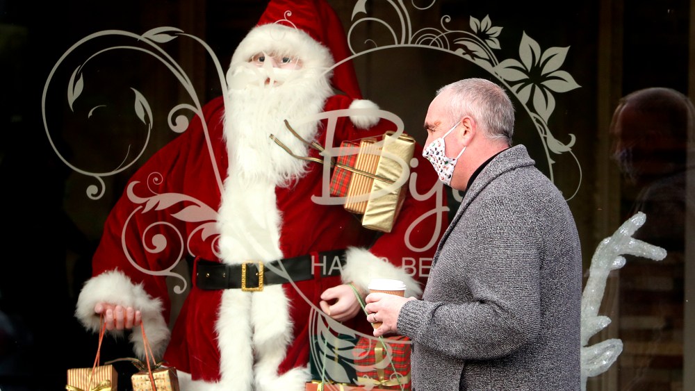 A person wearing a face covering walks past a Christmas window display at a hairdresser in Bathgate, West Lothian.