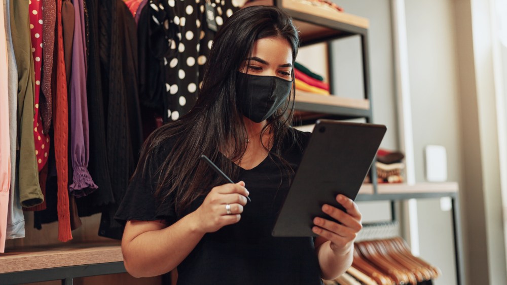 Latin woman owner of small business. Entrepreneurial woman working in her clothing store. Wearing face mask