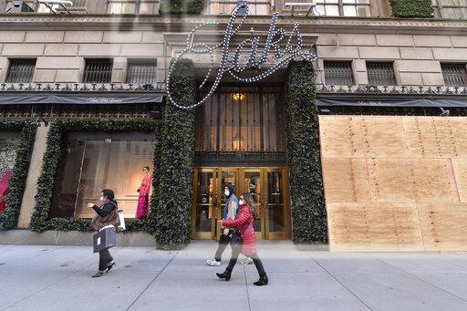 Pedestrians walk past the boarded up windows of the Saks Fifth Avenue flagship in New York on Saturday.
