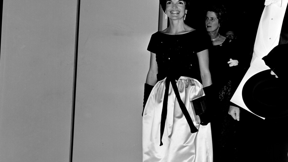 First Lady Jacqueline Kennedy and guest arrive for a performance at Lincoln Center for the Performing Arts in New York City on September 23, 1962. The First Lady wears a dress designed by Oleg Cassini.