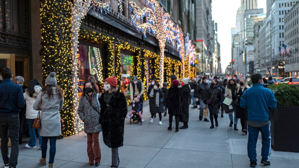 Masked shoppers and visitors walk down 5th Avenue and stop to look at the Saks 5th Avenue window displays for the Holiday season during the Coronavirus (Covid-19) outbreak in Manhattan,New York on Sunday, December 6, 2020. (Alex Menendez via AP)