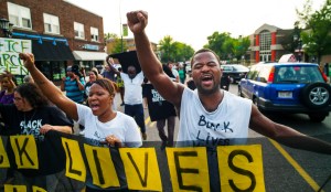 Protest leader, Rashad Turner, far right, leads dozens of protesters in a Black Lives Matter rally in the neighborhood around Governor's Mansion in St. Paul, Minn.