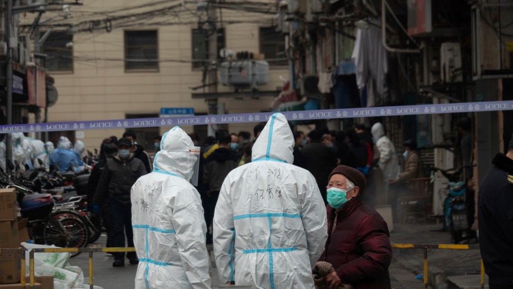 Government workers lock down a neighborhood in Huangpu district, the center of Shanghai, China Thursday, after a worker at a hospital found suspected of COVID-19 during a routine coronavirus test. Three new covid-19 cases were confirmed in the neighborhood by Thursday morning.
