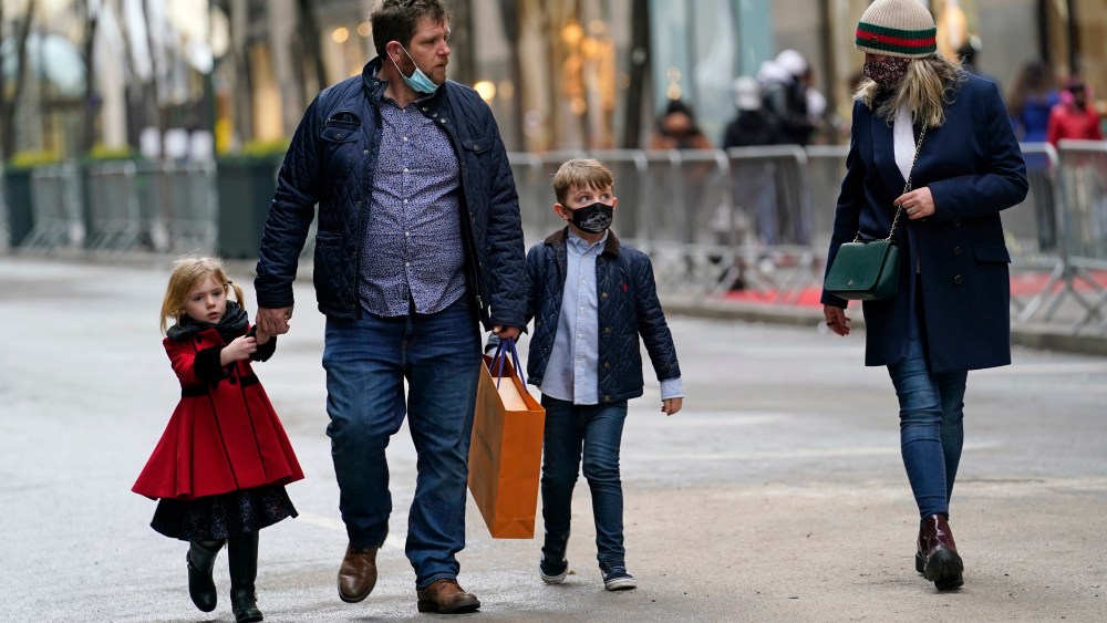 People walk down an empty street after shopping on Christmas Eve, Thursday, Dec. 24, 2020, in New York. (AP Photo/Kathy Willens)