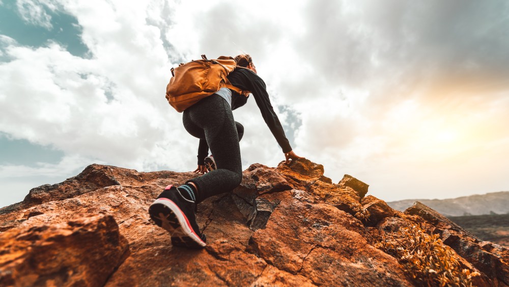 Success woman hiker hiking on sunrise mountain peak - Young woman with backpack rise to the mountain top. Discovery Travel Destination Concept