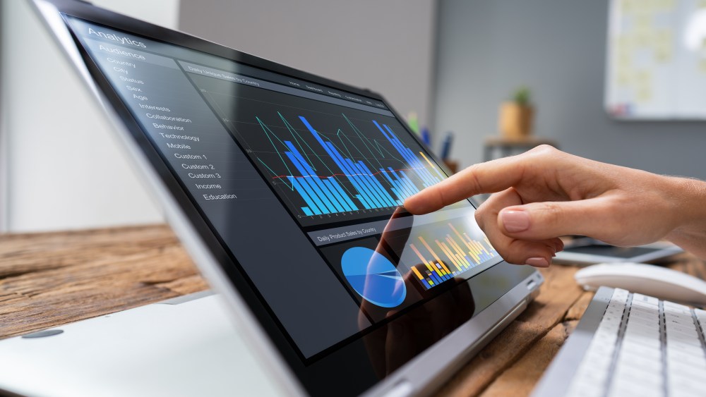 Close-up Of A Businesswoman's Hand Analyzing Graph On Laptop At Workplace