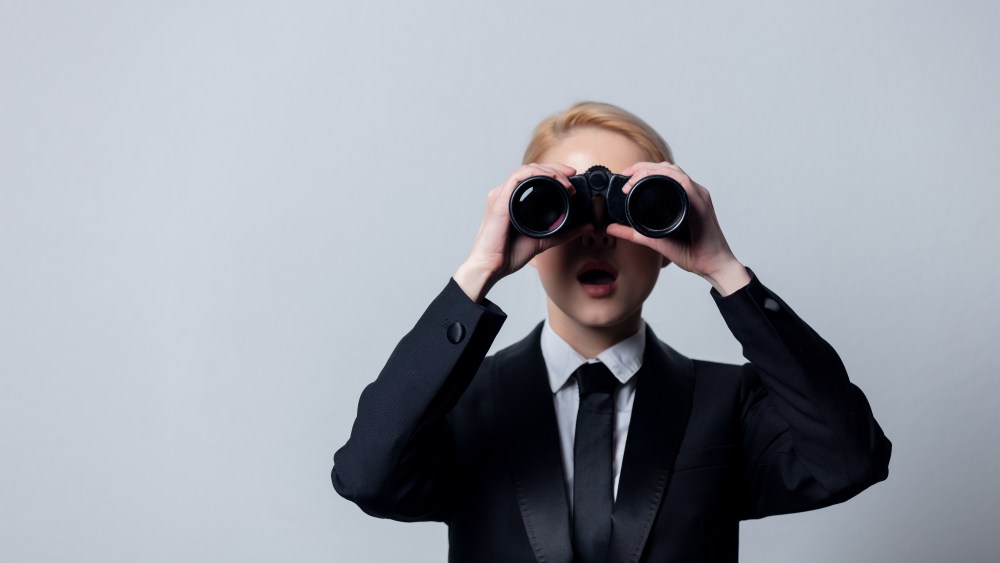 woman in suit looking through binoculars