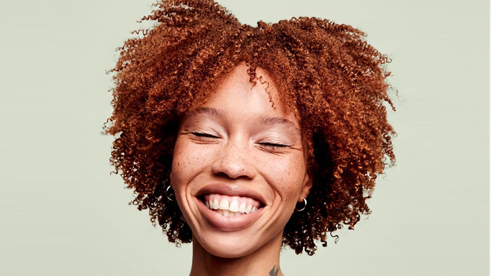 Curly hair model smiling from Devacurl hair conditioner