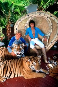 FILED - 30 November 1980, US, Las_Vegas: German-born American magicians and tamers Siegfried Fischbacher (l) and Uwe Horn, aka Roy (r), sit with their tigers on their estate. The "Siegfried & Roy" magician Siegfried Fischbacher is dead. The Rosenheim native died on Jan. 13, 2021, at the age of 81, his sister confirmed to the German Press Agency on Jan. 14. Photo by: Horst Ossinger/picture-alliance/dpa/AP Images