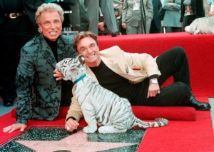 FILE - Illusionists Siegfried Fischbacher, left and Roy Uwe Ludwig Horn pose for photographers with a white tiger cub after they unveiled their star on the Hollywood Walk of Fame in Los Angeles, Calif., on Sept. 23, 1994. German news agency dpa is reporting that Fischbacher, the surviving member of duo Siegfried & Roy has died in Las Vegas at age 81. The news agency said Thursday that Fischbacher’s sister, a nun who lives in Munich, confirmed his death of cancer. Fischbacher’s long-time show business partner, Roy Horn, died in May of complications from COVID-19 at a Las Vegas hospital. (AP Photo/Neil Jacobs, File)