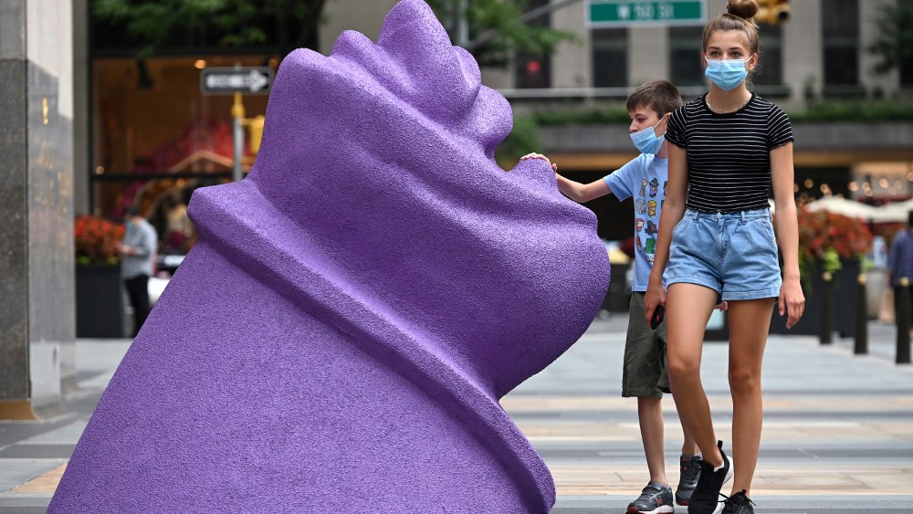 A young man stops to touch artist Lena Henke's R.M.M (Power Broker Purple) 2020 sculpture, part of the Frieze Sculpture exhibition at Rockefeller Plaza.