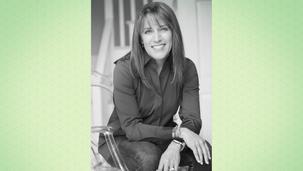 A professional greyscale headshot of Jill Standish smiling against a light green gradient background.