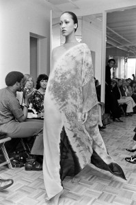 Model Pat Cleveland in a tye-died caftan from Halston fall 1972 ready to wear collection. Designer Ed Austin observes the show from the background.