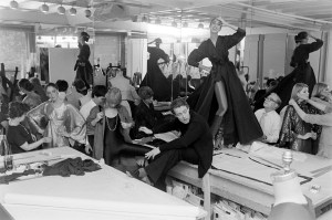 Halston and assistants fit models Pat Cleveland on the tabletop, Chris Royer, Kyle Traylor, and Shirley Farro in "body dressing" from Halston's Fall 1977 RTW advance.