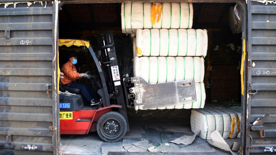 A forklift driver moves lint cotton produced in Xinjiang off a train at a railway freight station in Jiujiang in central China's Jiangxi province Friday, March 26, 2021.