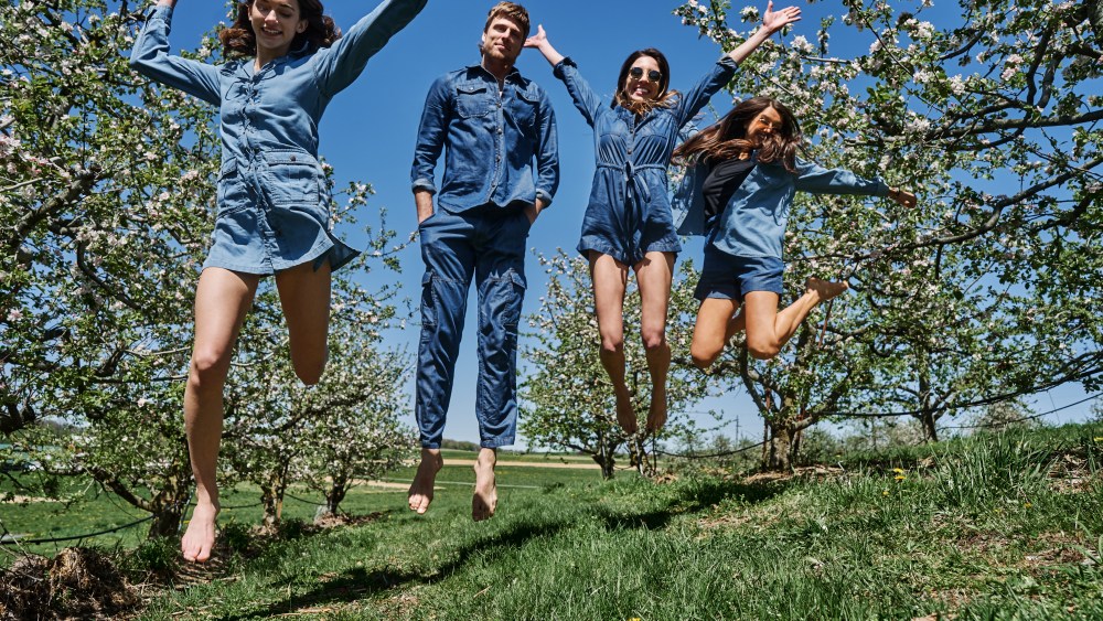 models wearing jeans and jumping in organic cotton field