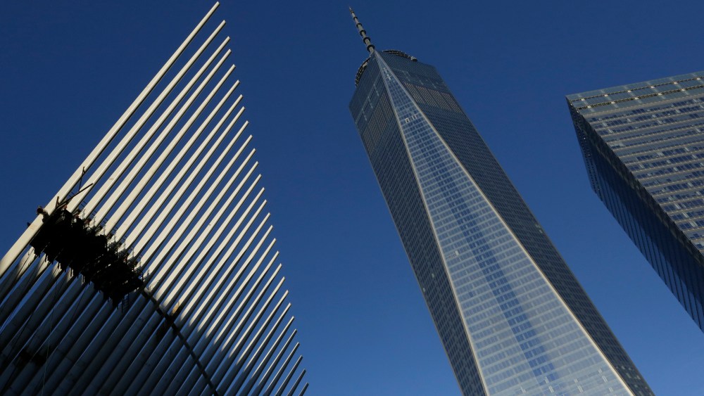 One World Trade Center stands between the transportation hub, left, still under construction, and 7 World Trade Center, right, Monday, Nov. 3, 2014 in New York. Thirteen years after the 9/11 terrorist attack, the resurrected World Trade Center is again opening for business, marking an emotional milestone for both New Yorkers and the United States as a whole. Publishing giant Conde Nast will start moving Monday into One World Trade Center, a 104-story, $3.9 billion skyscraper that dominates the Manhattan skyline. (AP Photo/Mark Lennihan)