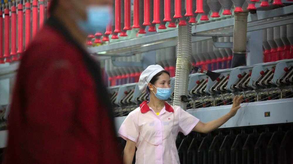 A worker checks machines processing cotton yarn at a Huafu Fashion plant, as seen during a government organized trip for foreign journalists, in Aksu in western China's Xinjiang Uyghur Autonomous Region, Tuesday, April 20, 2021. A backlash against reports of forced labor and other abuses of the largely Muslim Uyghur ethnic group in Xinjiang is taking a toll on China's cotton industry, but it's unclear if the pressure will compel the government or companies to change their ways. (AP Photo/Mark Schiefelbein)